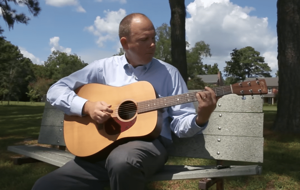 Dr. James Manning plays guitar outdoors.