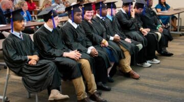 The nine 2024 Project SEARCH students sit together during their graduation at the Monroe Center in Greenville.