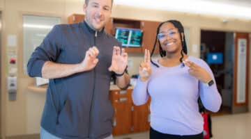 Two ECU Health interpreters sign out E-C-U-H to represent ECU Health.