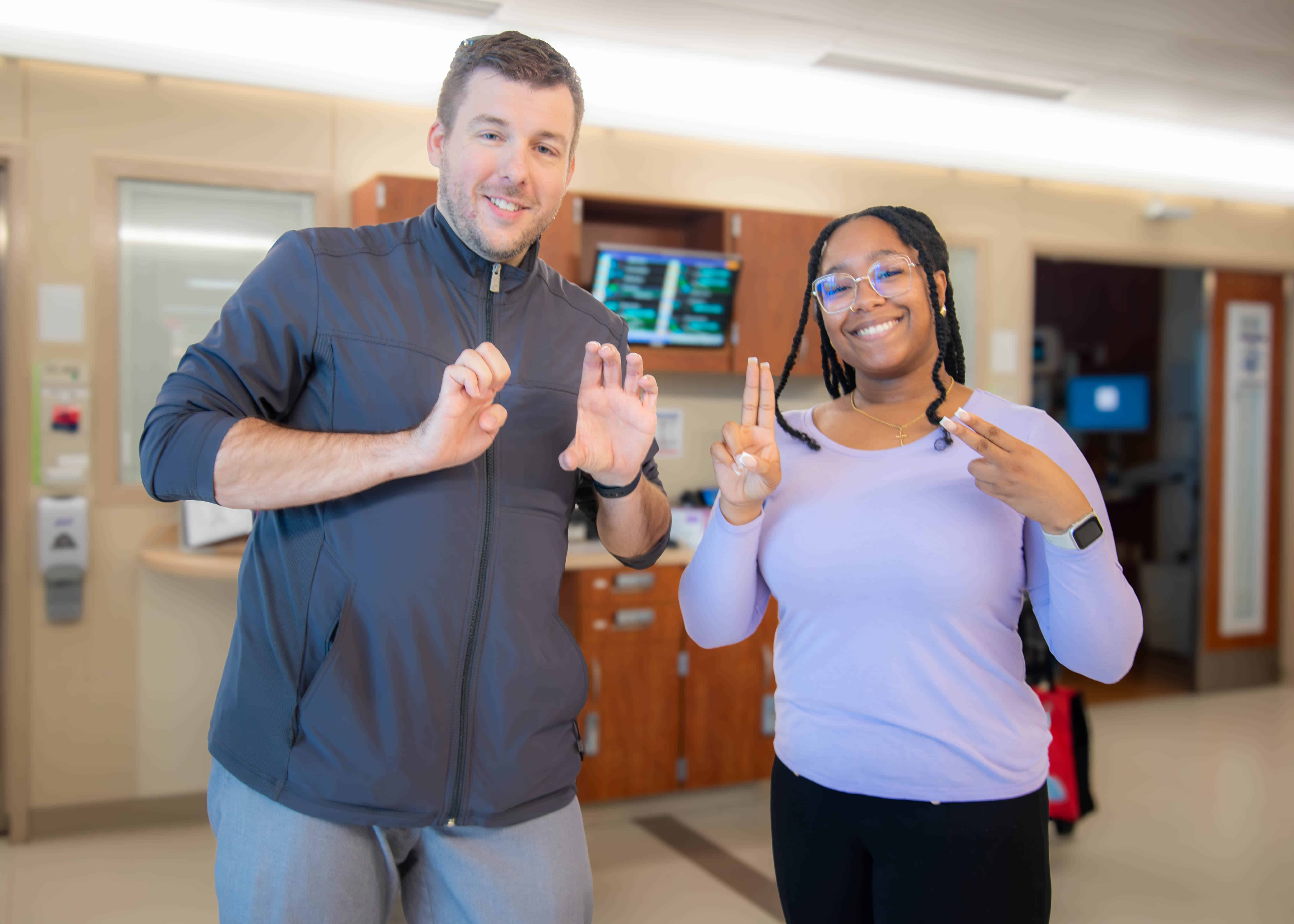 Two ECU Health interpreters sign out E-C-U-H to represent ECU Health.