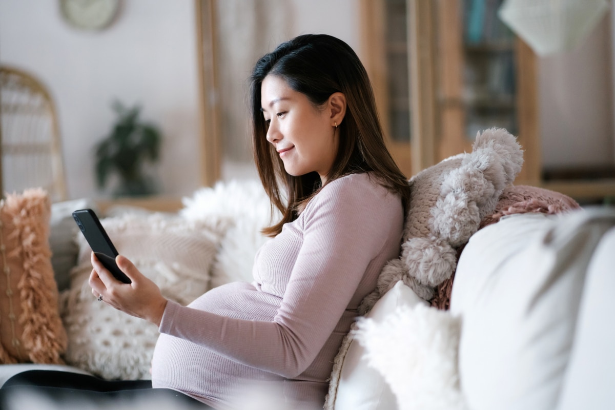 A pregnant woman checks her phone for updates on her health care.