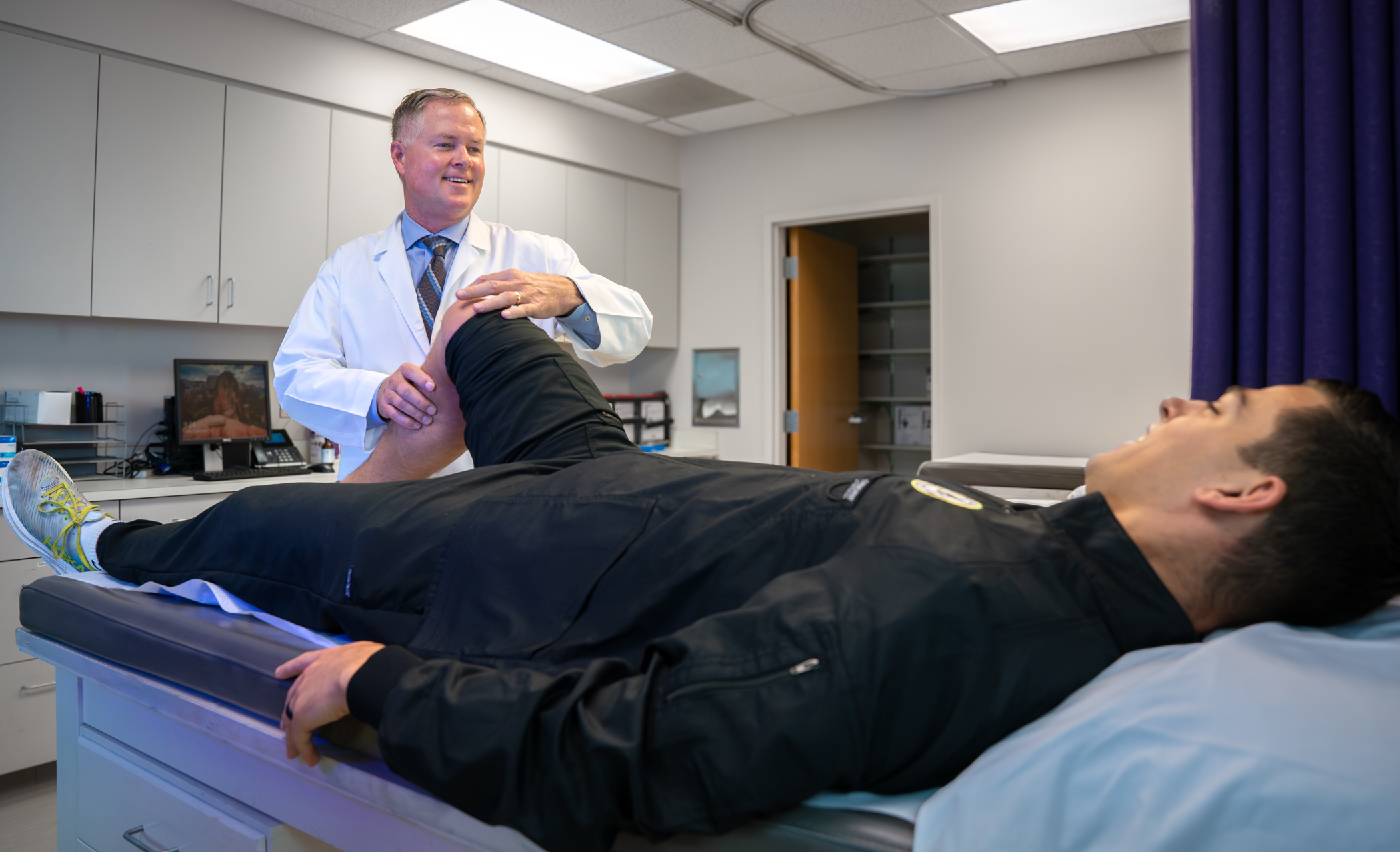 Dr. Christopher Hasty performs a knee exam.