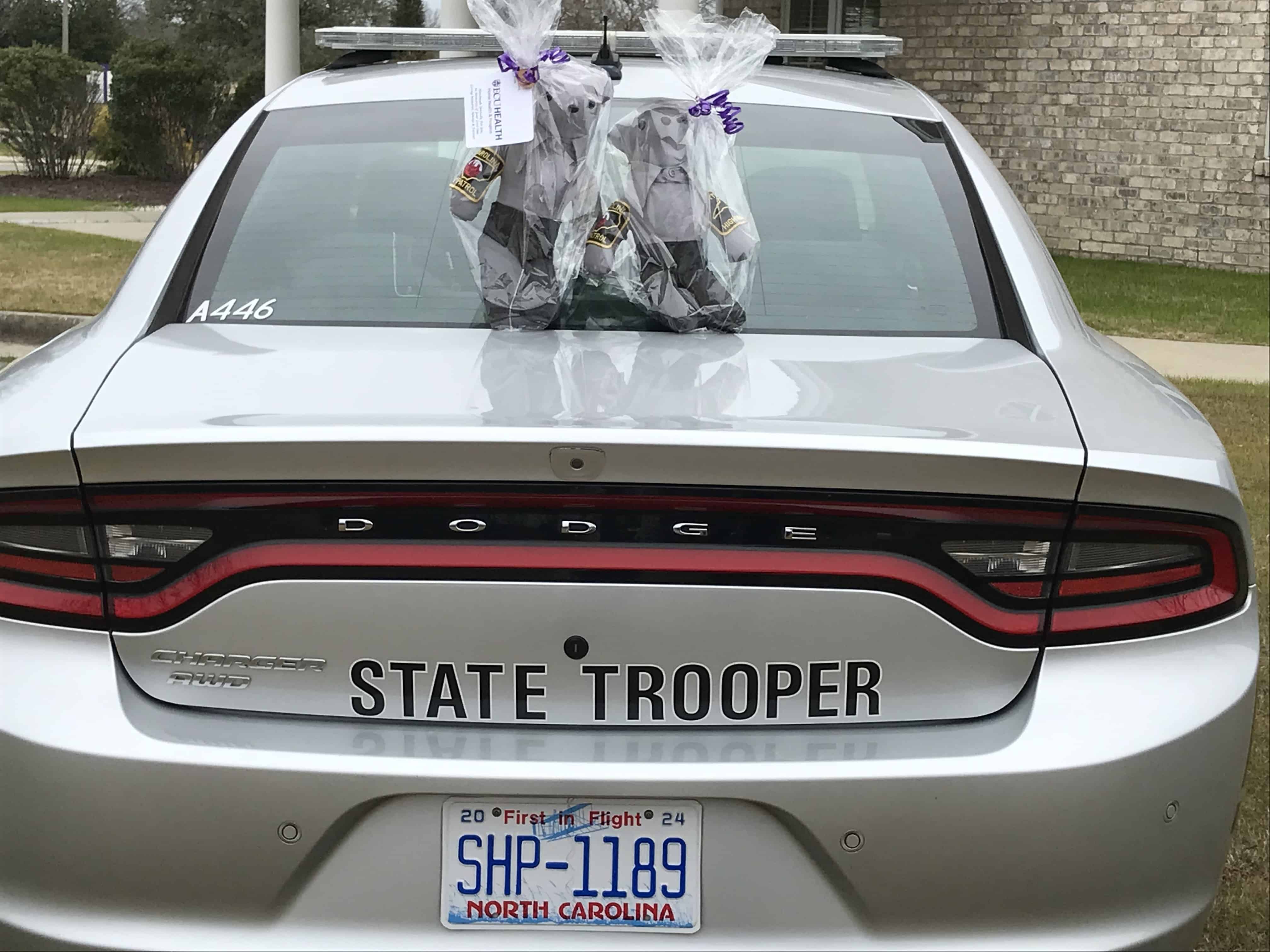 Memory bears made at Service League of Greenville Inpatient Hospice, made for Zach Martin's family, sit on top of a North Carolina State Trooper vehicle.